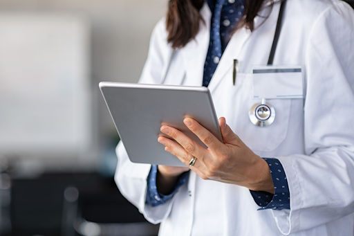 Doctor using a digital tablet for patient care management and health monitoring in a clinical setting.