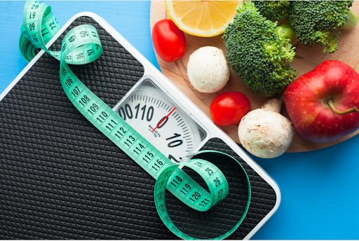 Scale with measuring tape and vegetables, representing healthy weight management.