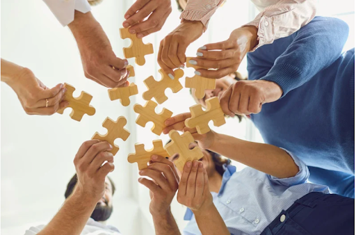 Multiple hands coming together to hold puzzle pieces, illustrating the impact of socioeconomic status on COPD outcomes.