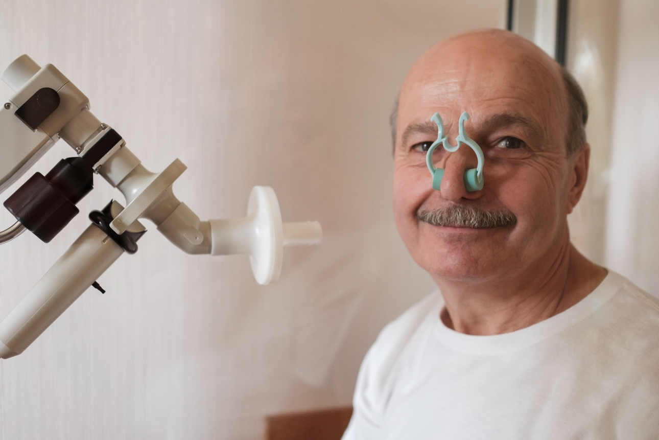 Elderly man preparing for a spirometry test to assess lung function.