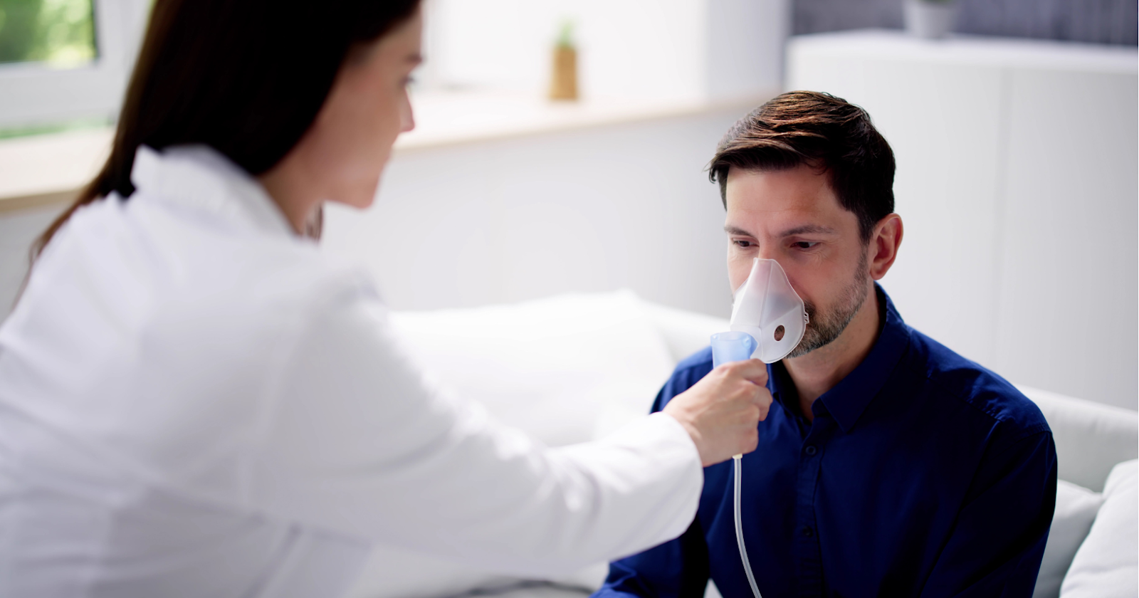 Doctor administering oxygen therapy to a man as a part of COPD treatment.