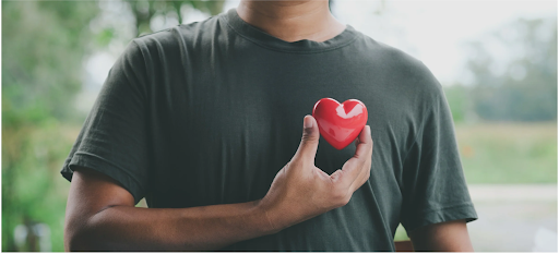 Man holding a red heart symbol on his chest to signify heart health in COPD.