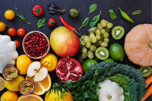 Collection of colorful fruits and vegetables on a dark background, representing healthy eating.