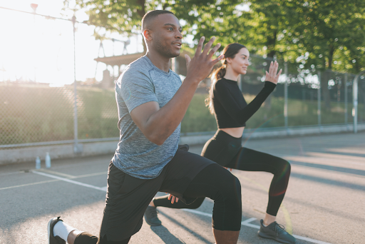 Young man and woman performing lunges during an outdoor workout.