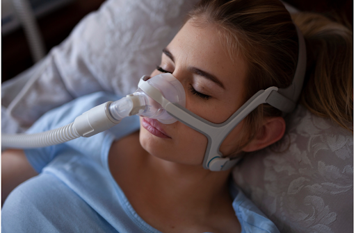 A woman sleeping while wearing a non-invasive nasal oxygen therapy mask.