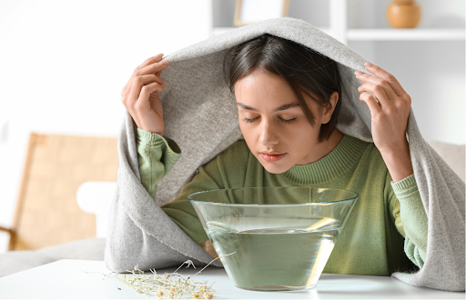 A woman inhales steam from a bowl with a towel over her head as part of a home-based salt inhalation respiratory therapy.