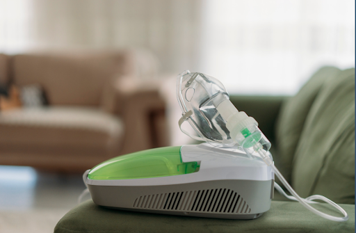 A nebulizer with a face mask lying on a table in a home setting for respiratory therapy.