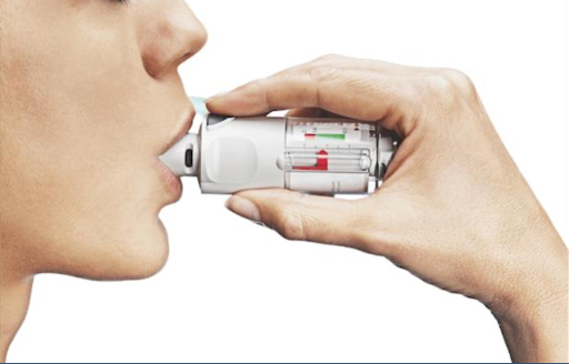 A woman using a soft mist inhaler (SMI) to take her medication for COPD treatment.