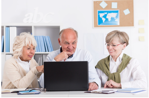 An elderly man learning about COPD management with caregivers using a laptop, illustrating the need for patient education.
