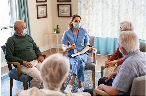 A healthcare professional leads a group discussion with elderly individuals wearing masks in a cozy room setting, symbolizing support and shared experiences in managing COPD.